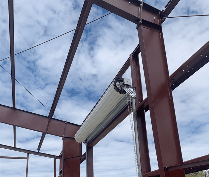 Red iron steel building frame with hot-rolled I-beams and open web structure during construction, showcasing strength and wide-span capability.