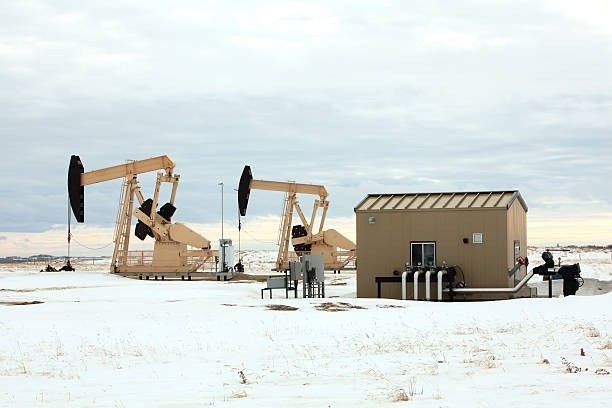 Pre-engineered steel buildings and pump jacks at an oilfield site in Texas with snow-covered ground, showcasing rugged infrastructure for energy sector use.
