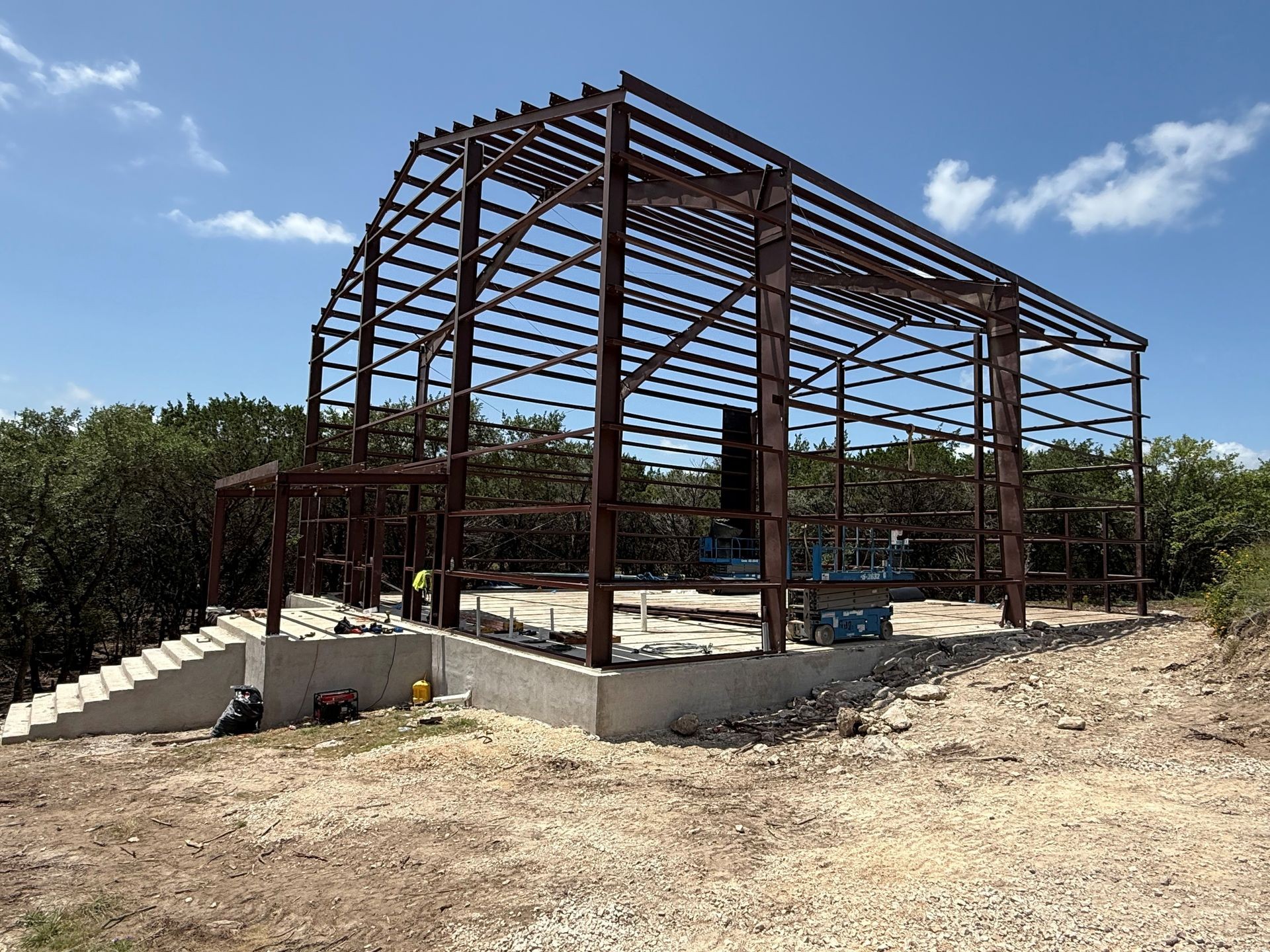 Metal skeletal structure of a building under construction with a clear blue sky in the background.