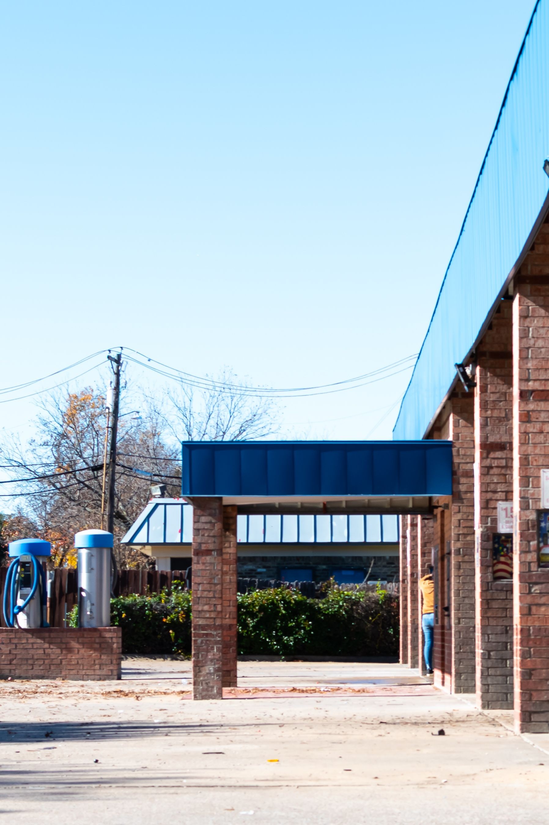 Woman in the distance using a self service car wash stall