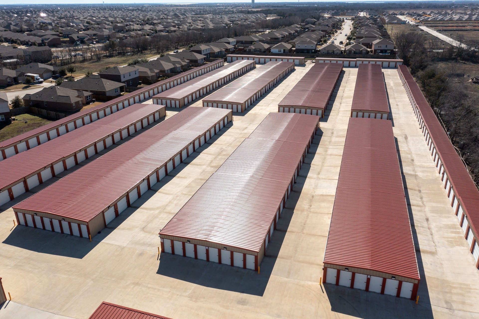 Aerial view of multiple red-roofed mini storage units with drive-up access
